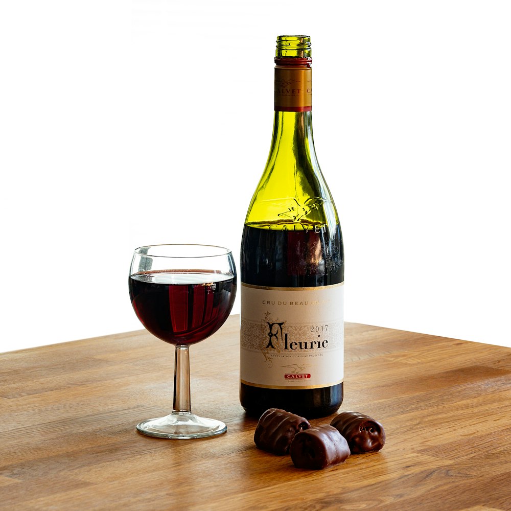 茶色の木製のテーブルの上のワイングラスの横に白いラベルのボトル