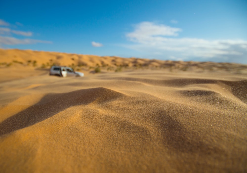 SUV blanco en arena marrón bajo cielo azul durante el día