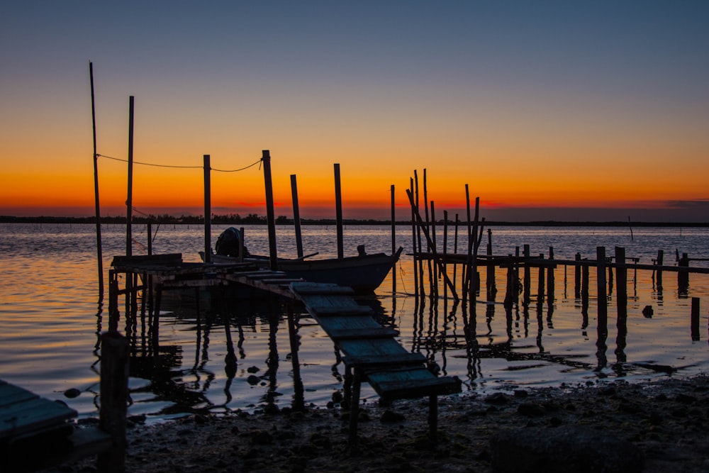 silhouette of wooden dock on sea during sunset