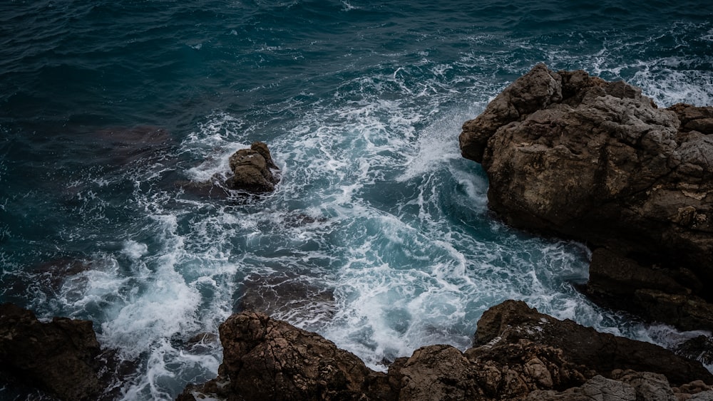 brown rock formation on body of water during daytime