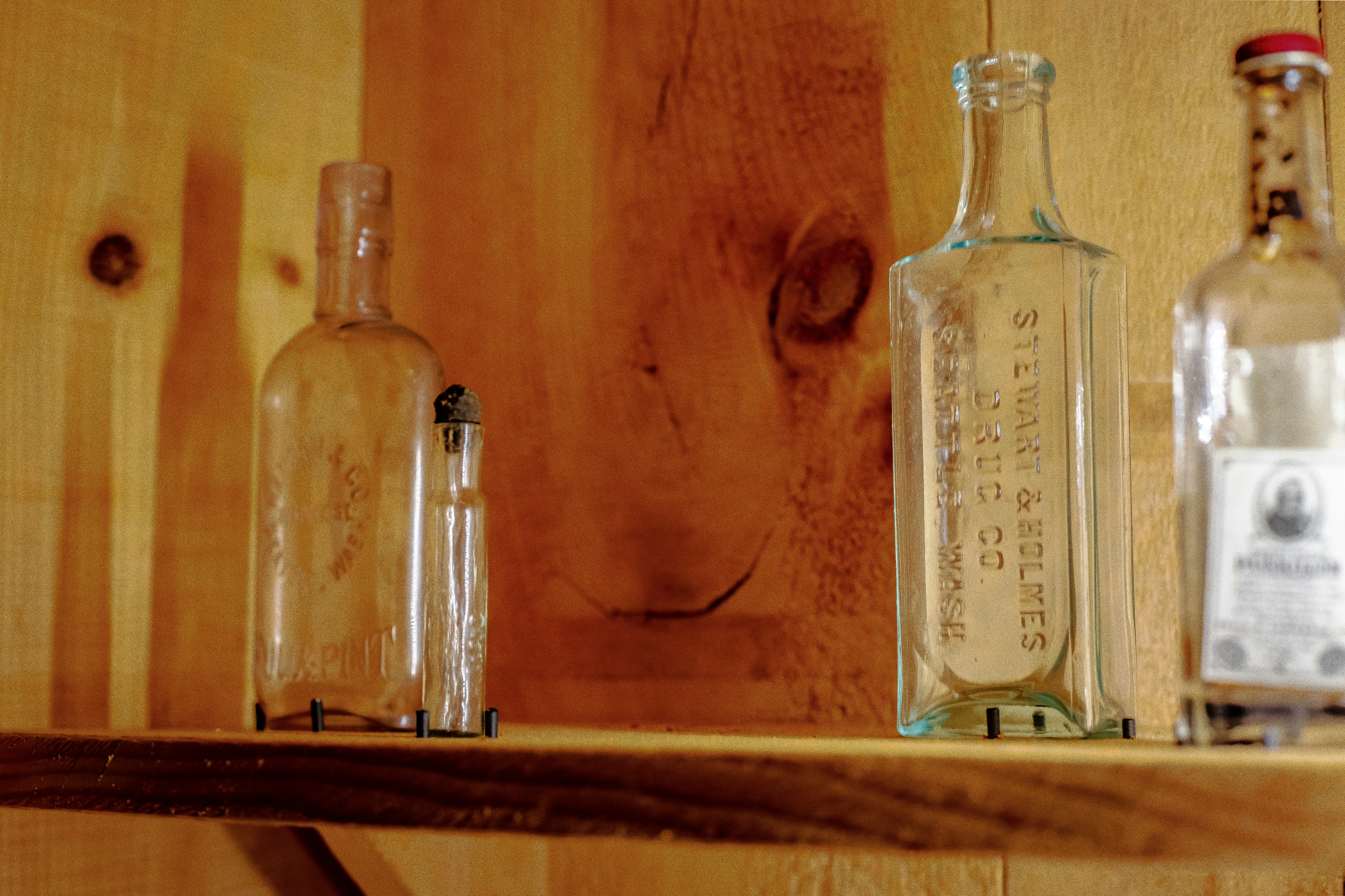 clear glass bottle on brown wooden shelf