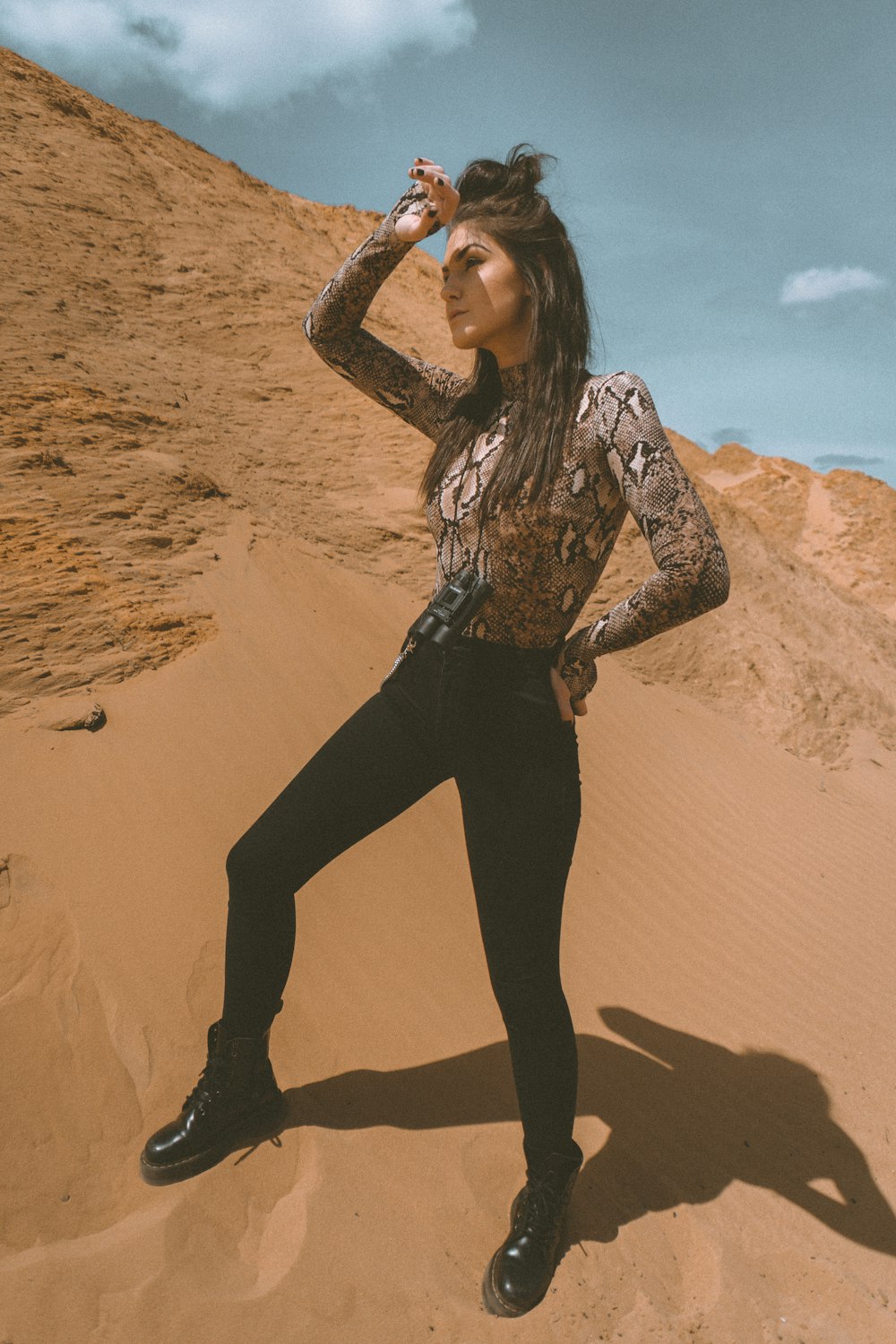 woman in black pants and brown and white long sleeve shirt on brown sand during daytime