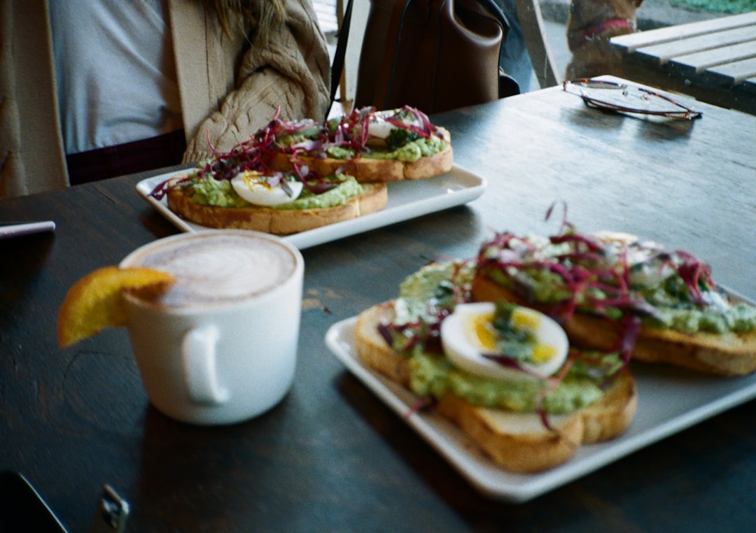 sliced pizza on white ceramic plate, Half-Frame Film Photo of Avocado Toast and an Orange Latte. Shot on Kodak Ultramax 