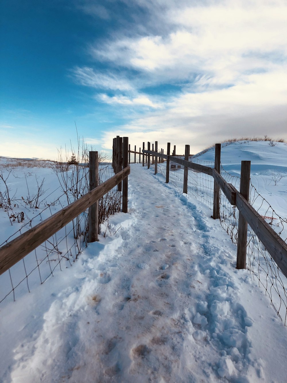 brown wooden fence on snow covered ground under blue sky during daytime