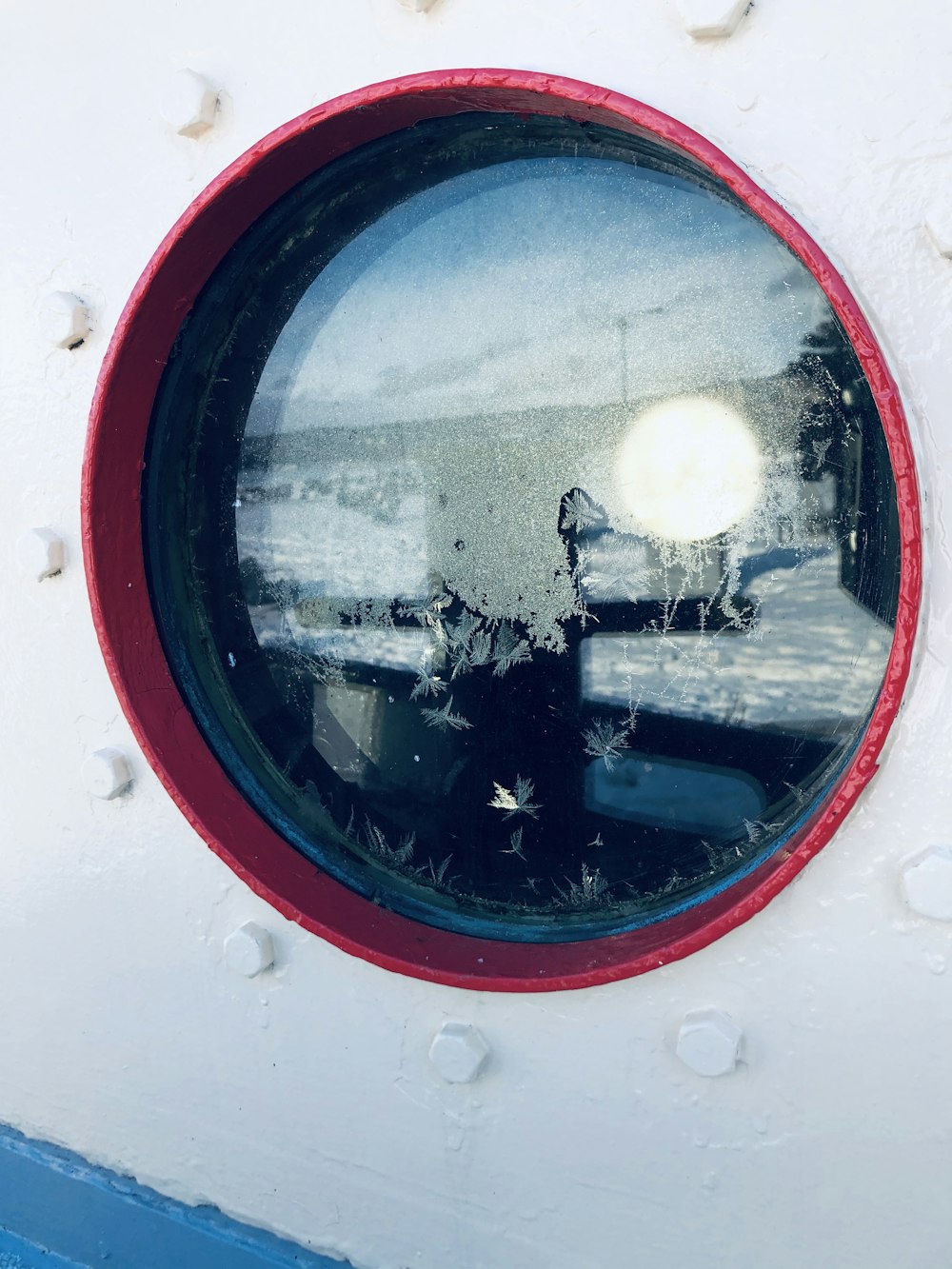 red framed round mirror reflecting white building