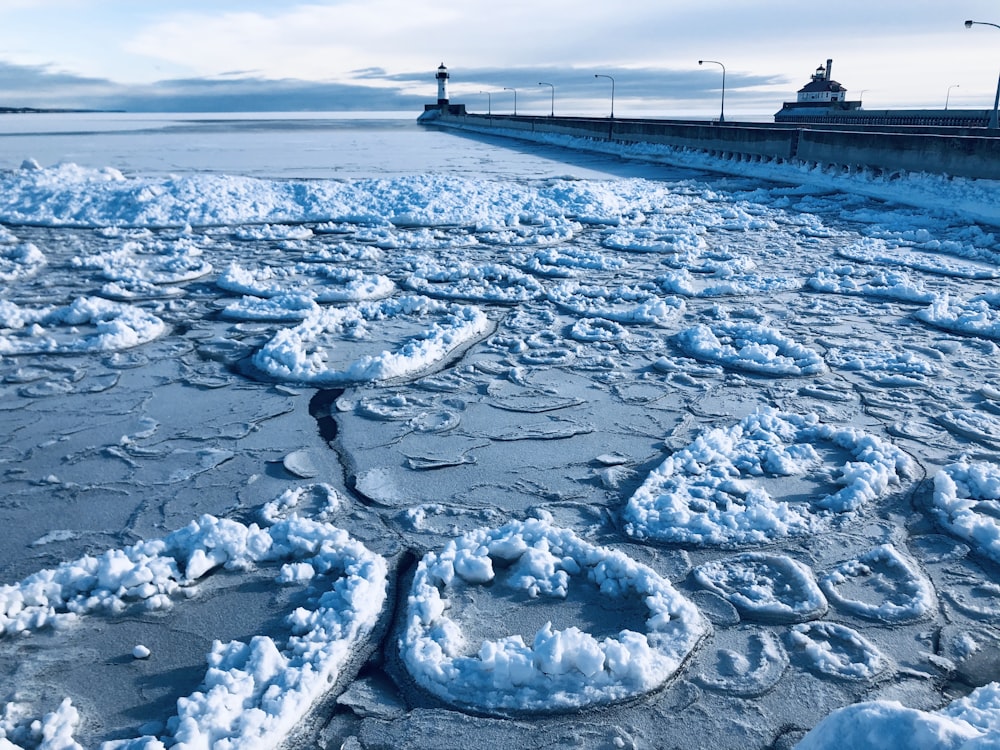 person standing on white snow covered ground near body of water during daytime