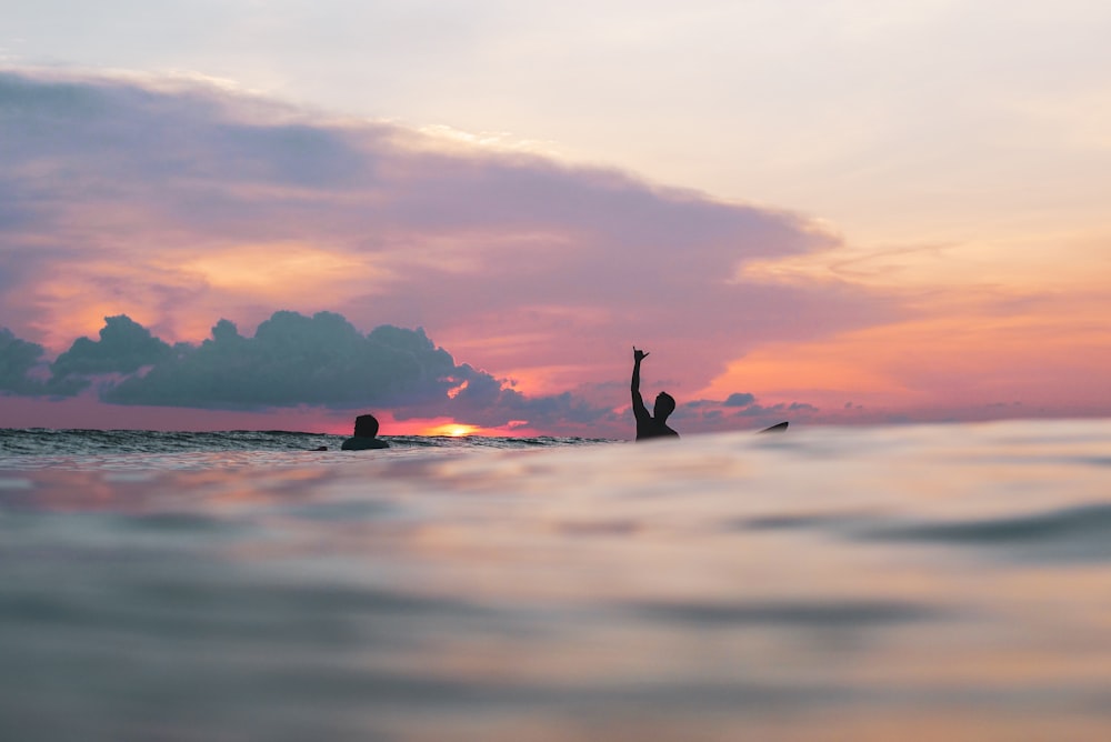 silhouette of person surfing on sea during sunset