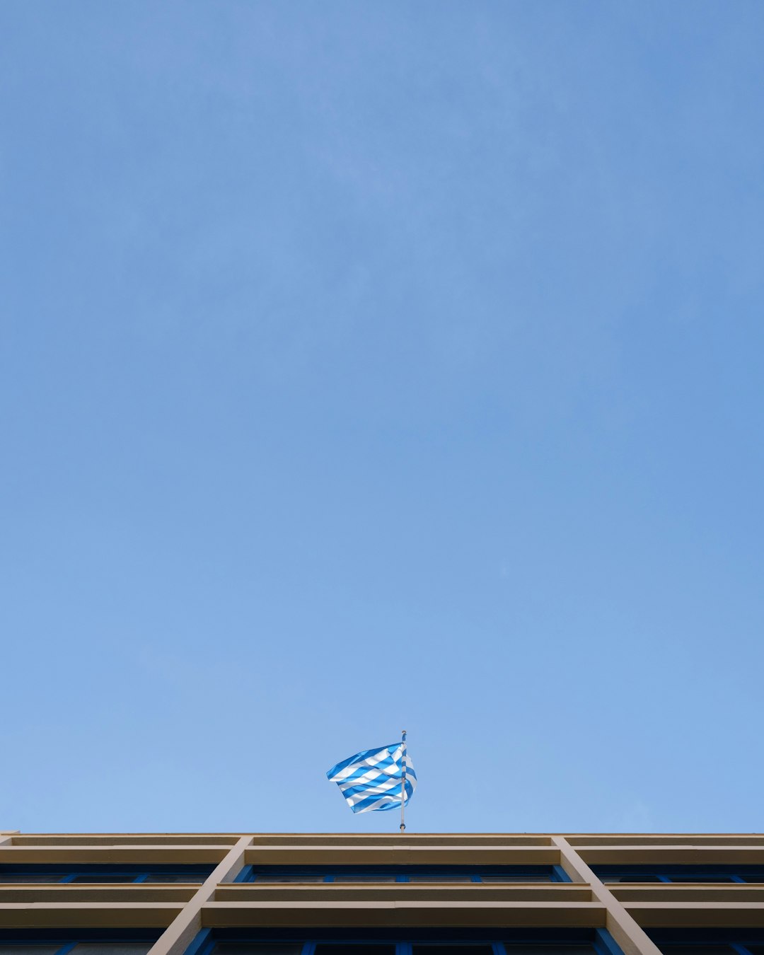blue and white striped flag on pole under blue sky during daytime
