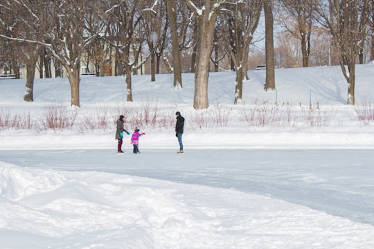 2 children walking on snow covered ground during daytime in Parc La Fontaine Canada