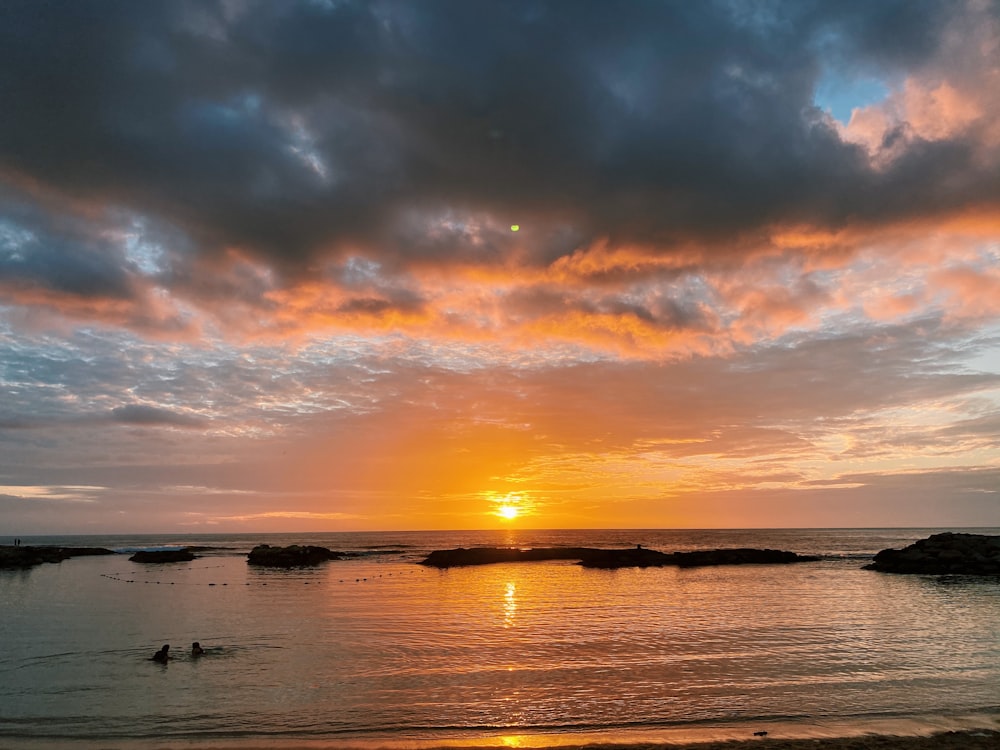 body of water under cloudy sky during sunset