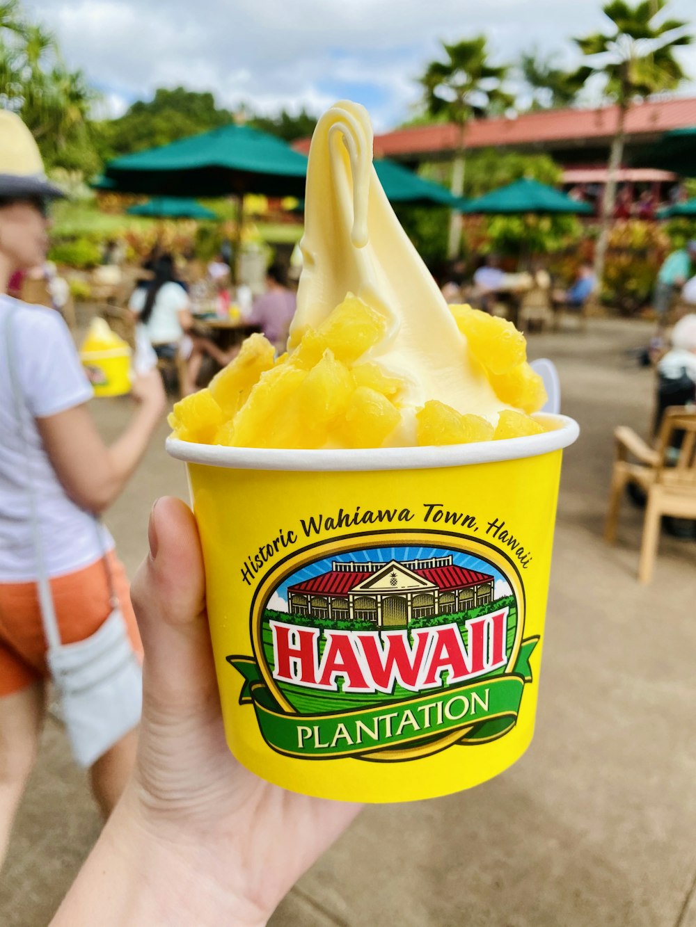 person holding a blue and yellow cup with yellow ice cream