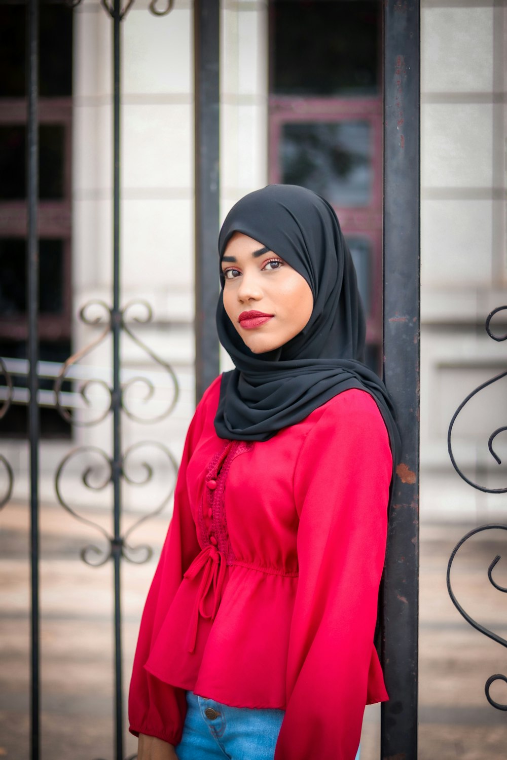 a woman wearing a hijab standing next to a fence