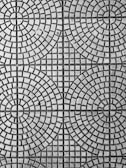 An intricate pattern of circular and square shapes on a textured surface. The design consists of evenly spaced concentric circles intersected by straight lines, creating a symmetrical and geometric appearance.