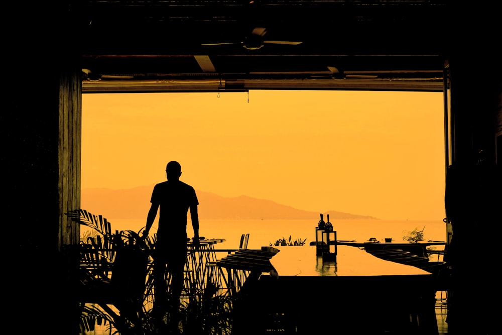 silhouette of man standing on dock during sunset