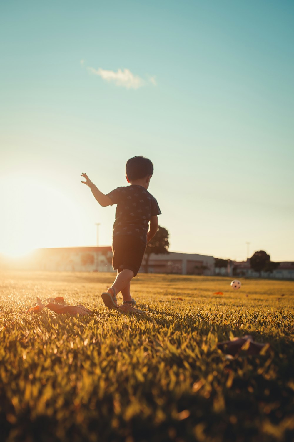 boy in black shirt running on green grass field during daytime