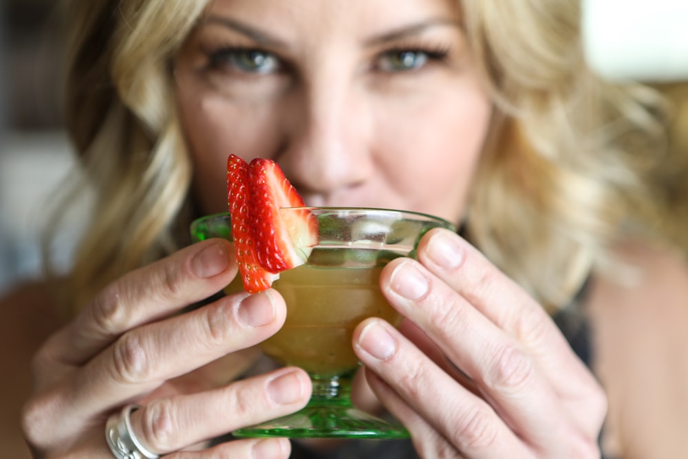 woman holding clear glass cup with strawberry juice