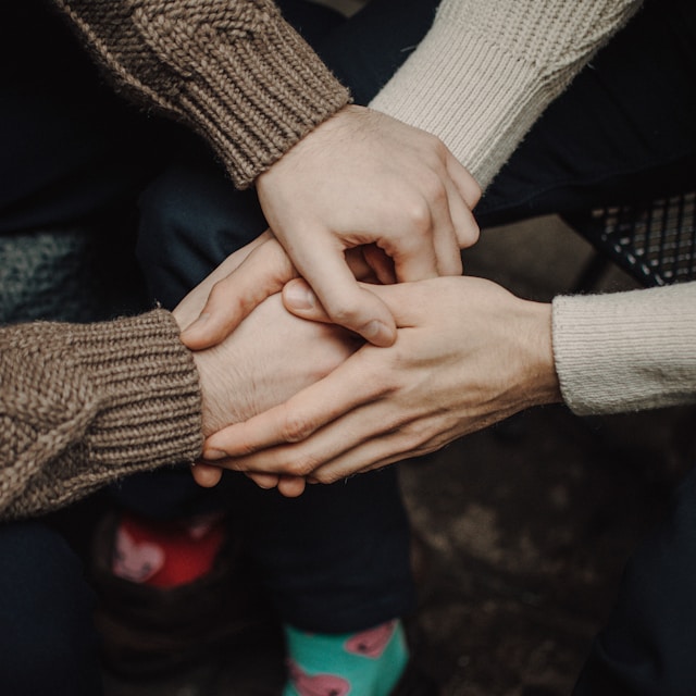 person in gray sweater holding hands of person in black long sleeve shirt