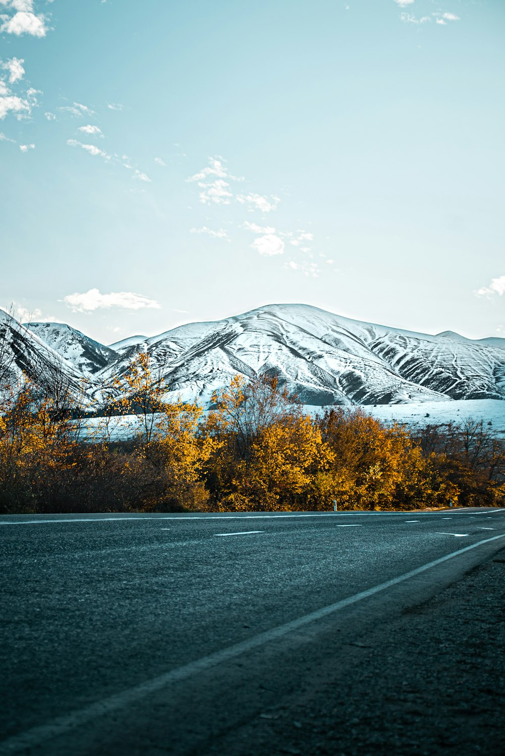 gray asphalt road near snow covered mountain during daytime