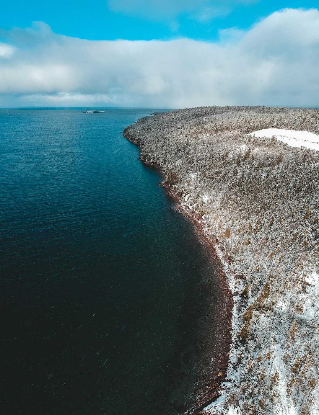 white and black rock formation near blue sea under white clouds during daytime