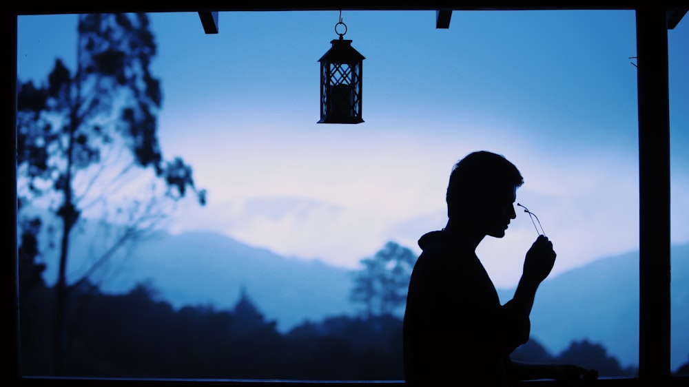 silhouette of man standing near lantern during daytime