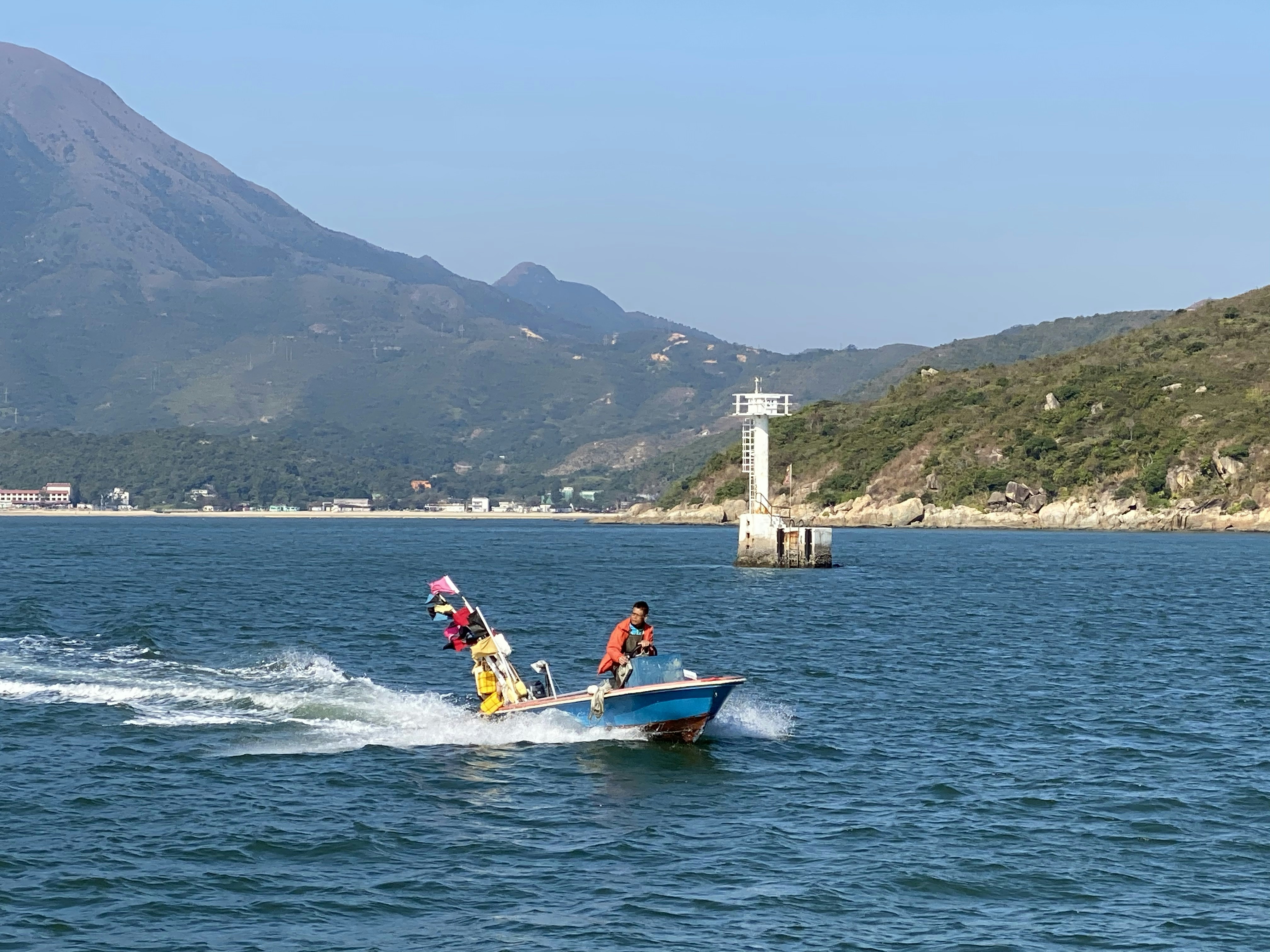 man in red shirt riding on blue and white boat on sea during daytime