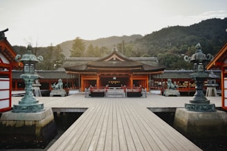 A serene traditional Japanese temple surrounded by lush greenery under soft morning light.