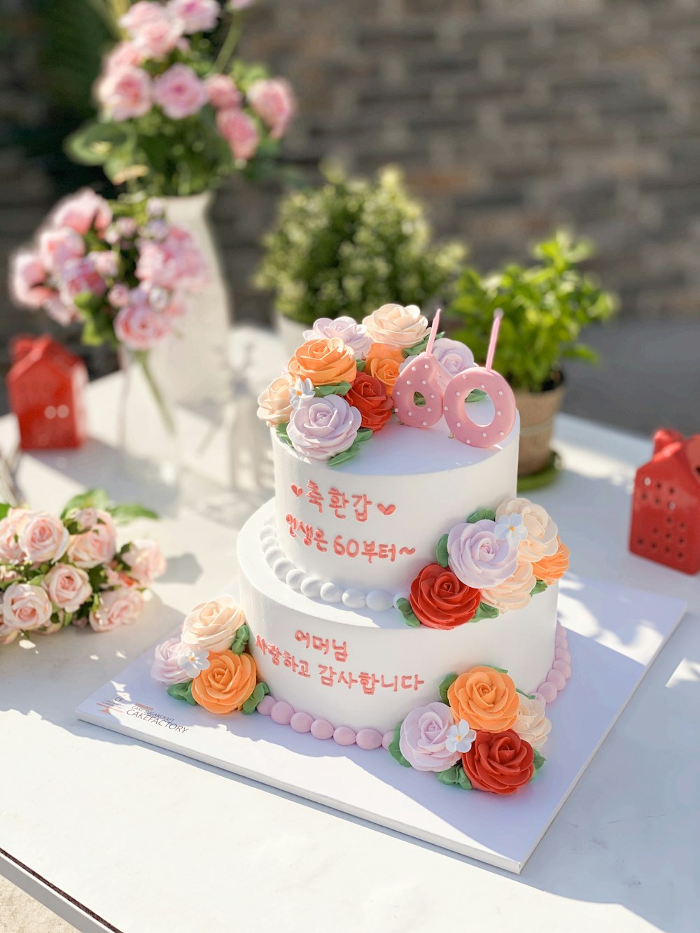 white and pink floral cake with red and white flower on top