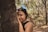girl in black tank top leaning on brown tree during daytime