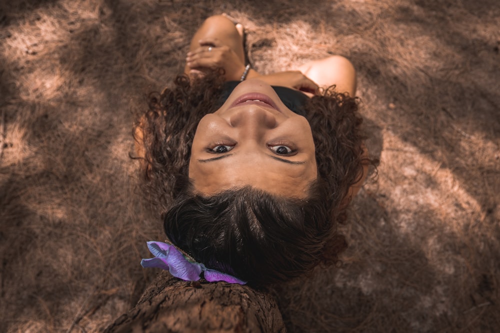 woman in purple sleeveless dress lying on brown sand during daytime