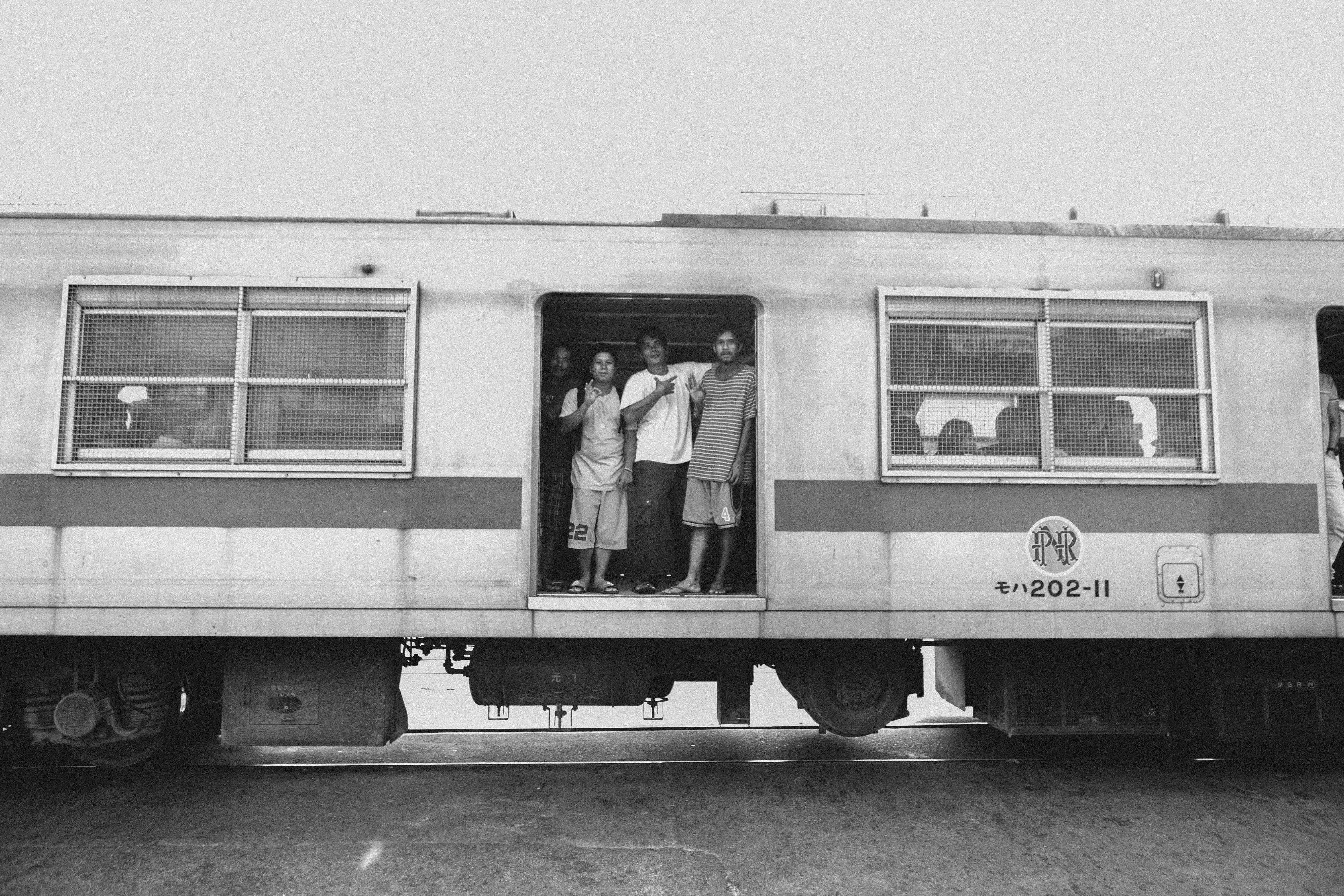 grayscale photo of man and woman standing in front of white and black train