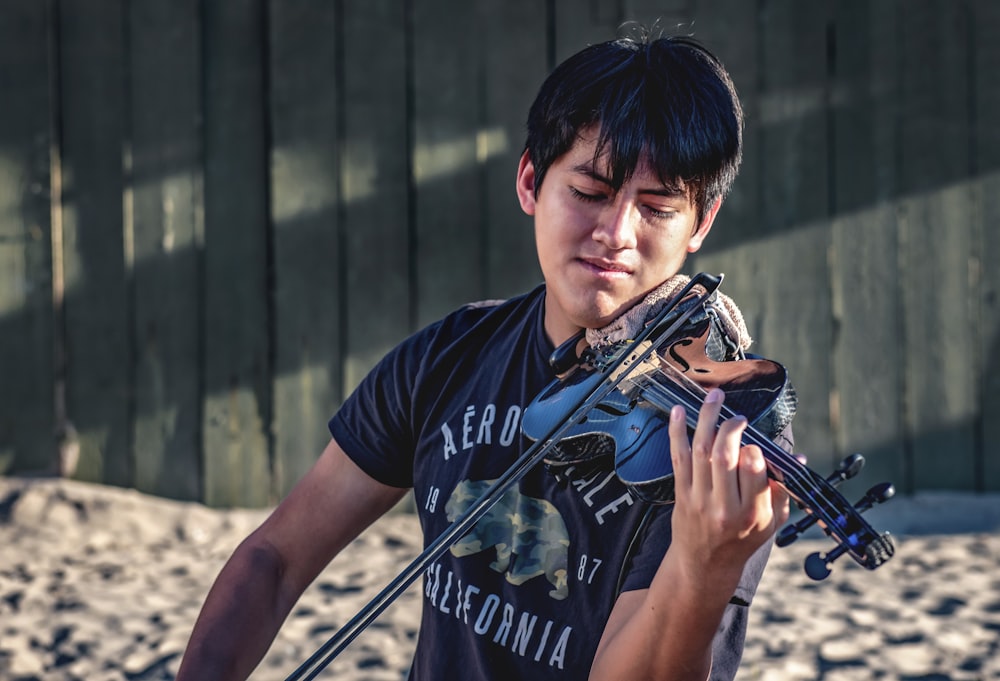 man in blue and white crew neck t-shirt playing violin