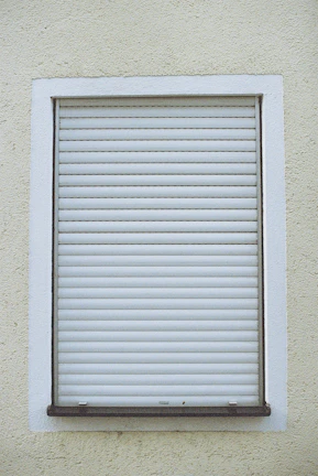 Close-up of a sleek blue and white roller shutter partially closed on a modern home