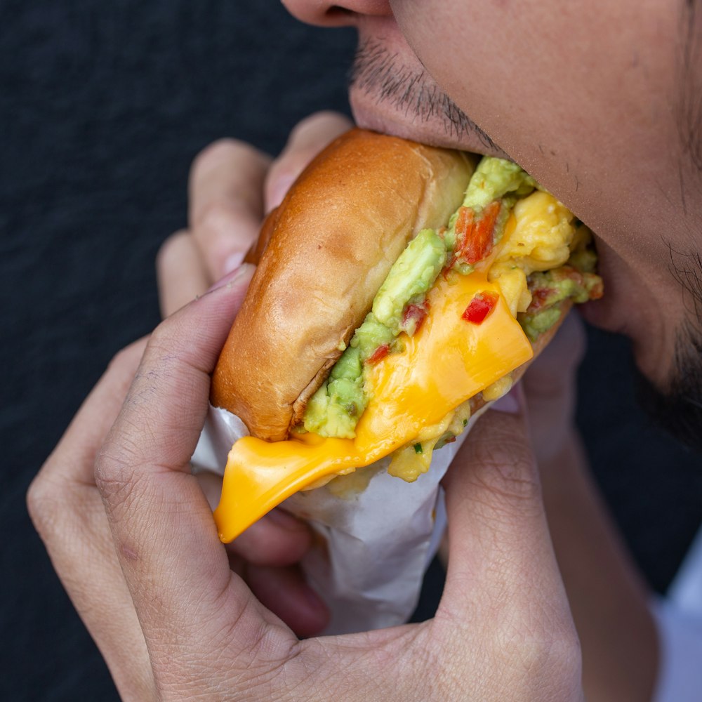 person holding burger with cheese