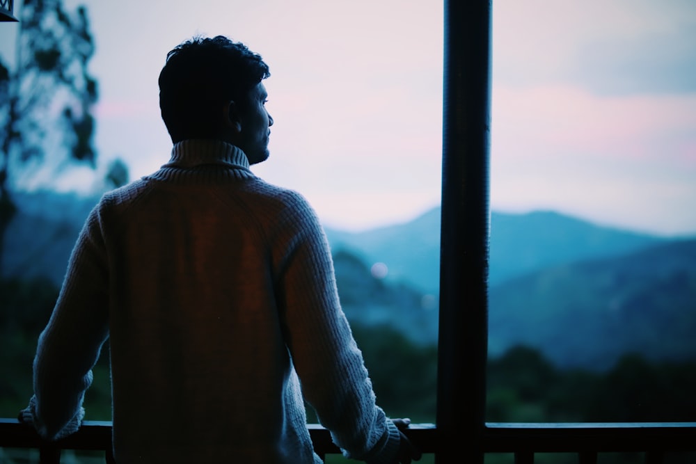 man in brown sweater looking at the city during daytime