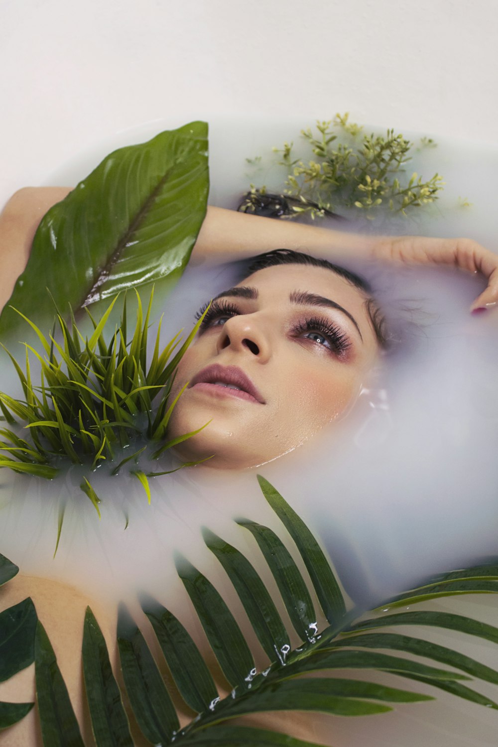 woman in white shirt lying on green leaves