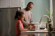 man in long sleeve shirt standing beside girl in pink tank top washing hands
