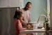 man in long sleeve shirt standing beside girl in pink tank top washing hands