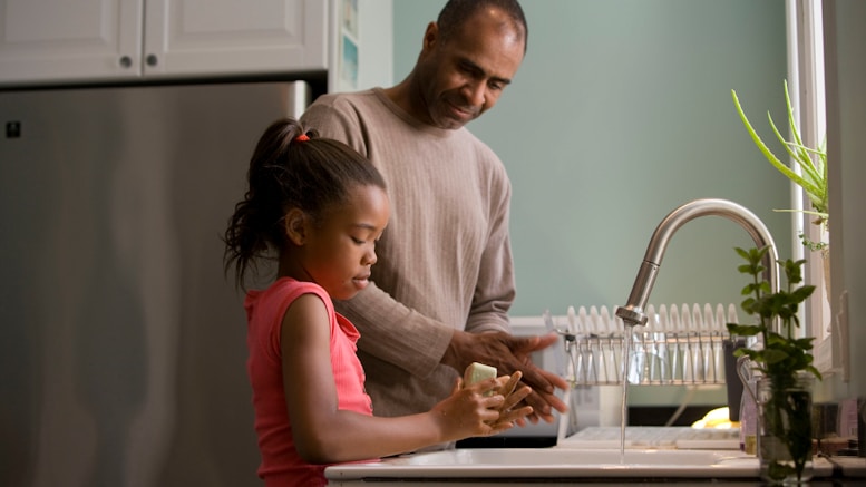 man in long sleeve shirt standing beside girl in pink tank top washing hands