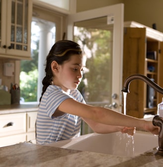 woman in blue and white stripe shirt washing her hands