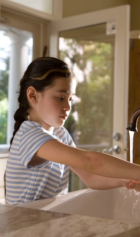 woman in blue and white stripe shirt washing her hands