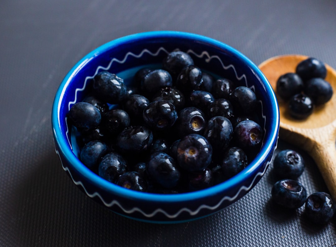 black round fruits on blue and white ceramic bowl