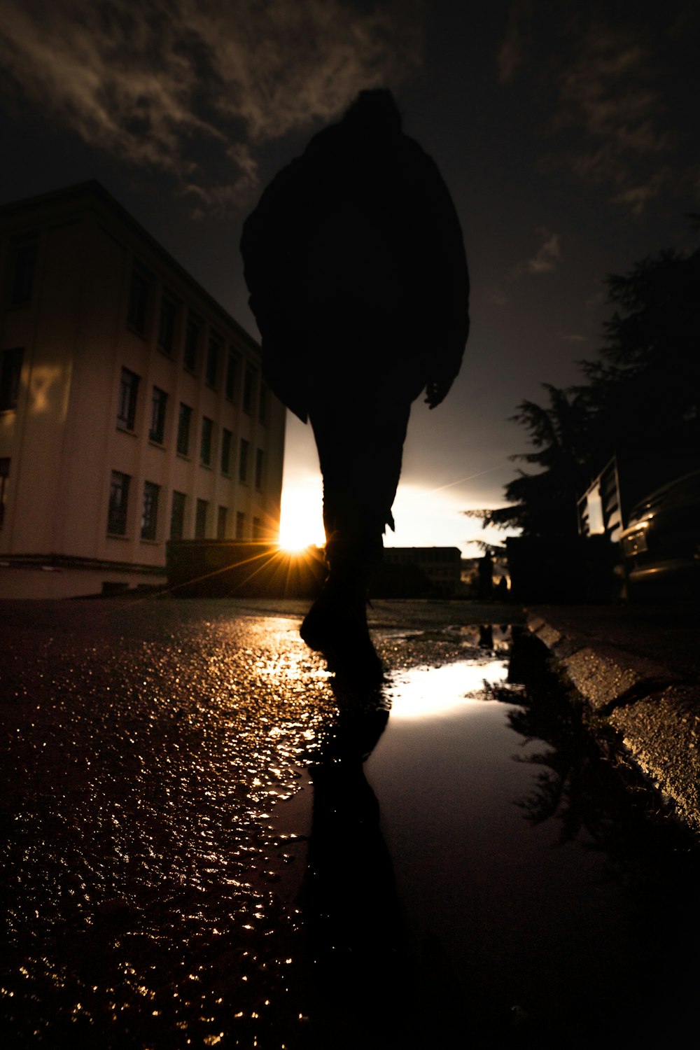 silhouette of person walking on wet road during night time