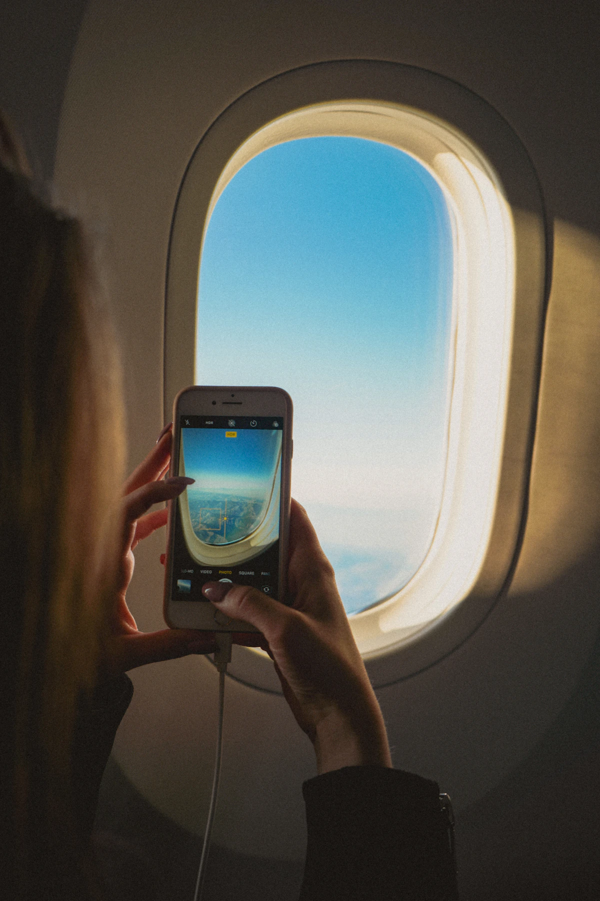 Passenger holding a smartphone beside an airplane window