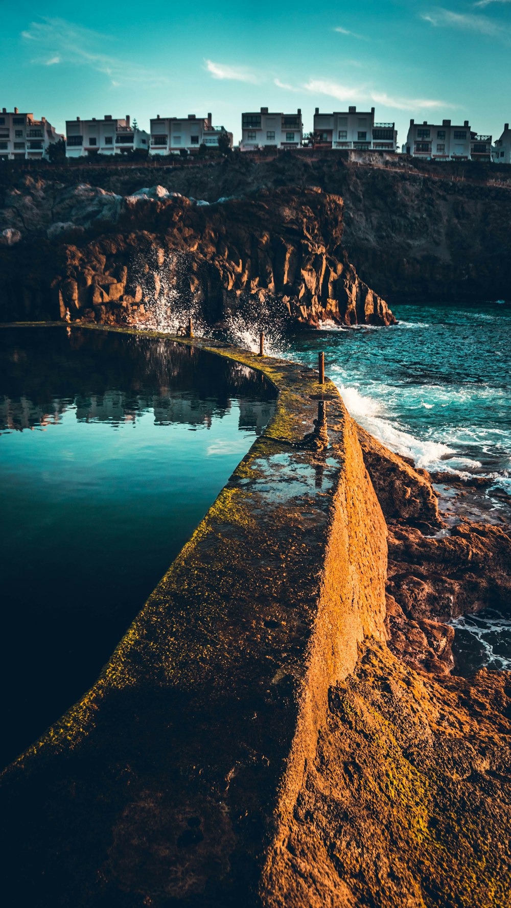 brown concrete pathway beside body of water during daytime