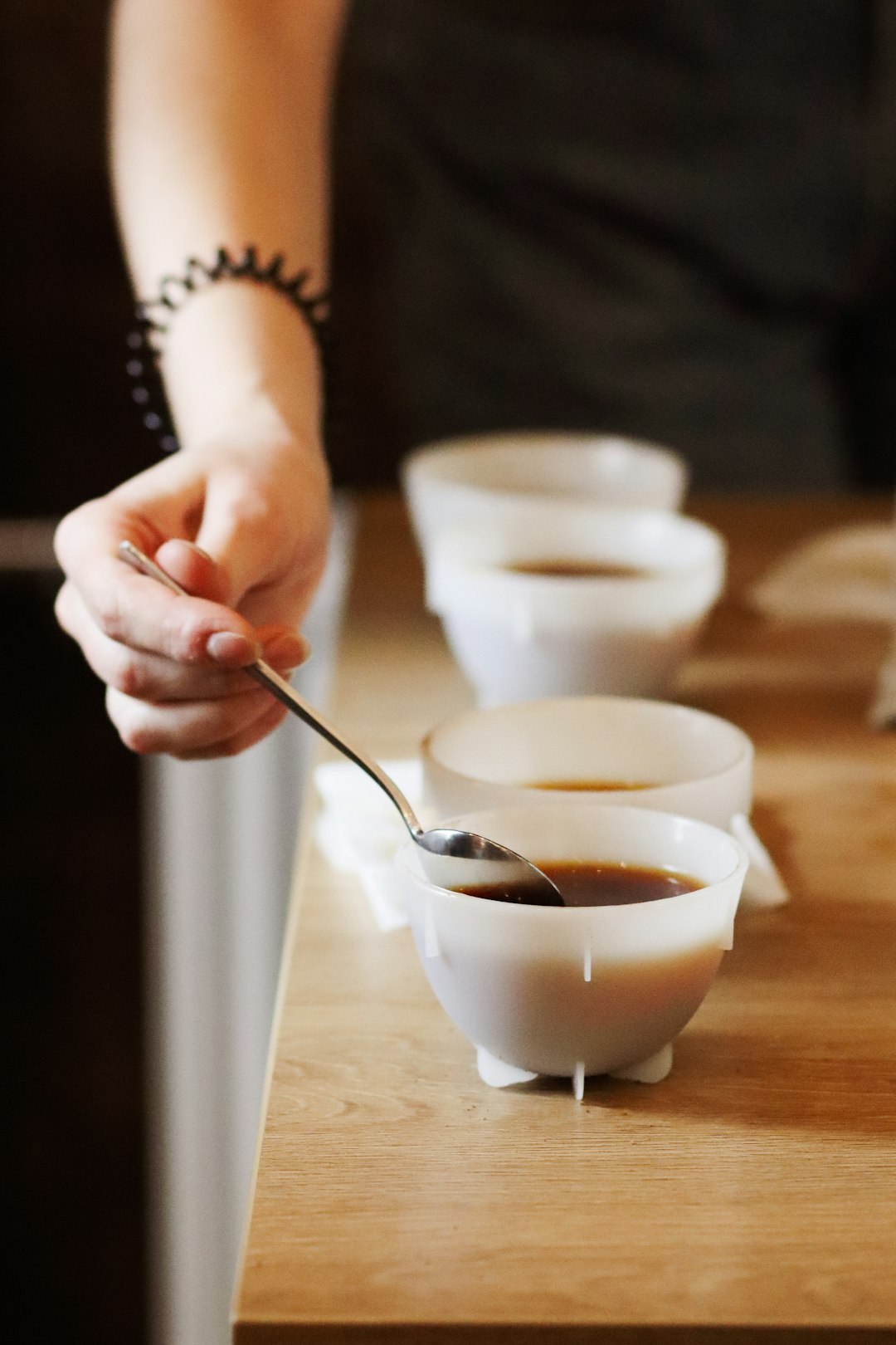 person holding silver spoon pouring white liquid on white ceramic cup