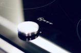 Close-up view of a modern stovetop with a metallic knob and the brand logo 'NEFF' displayed prominently. The surface is sleek and shiny with reflections.