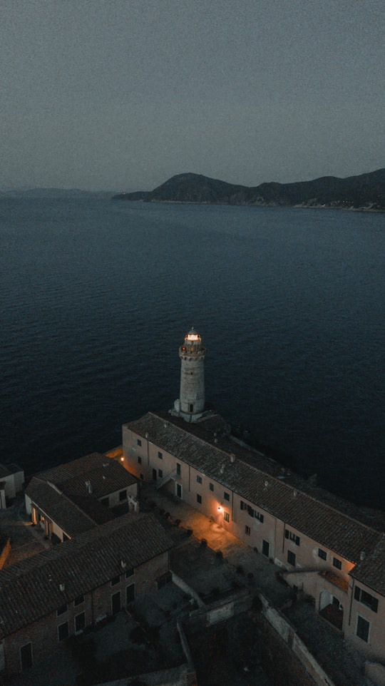 white concrete lighthouse near body of water during daytime in 57037 Portoferraio Italy