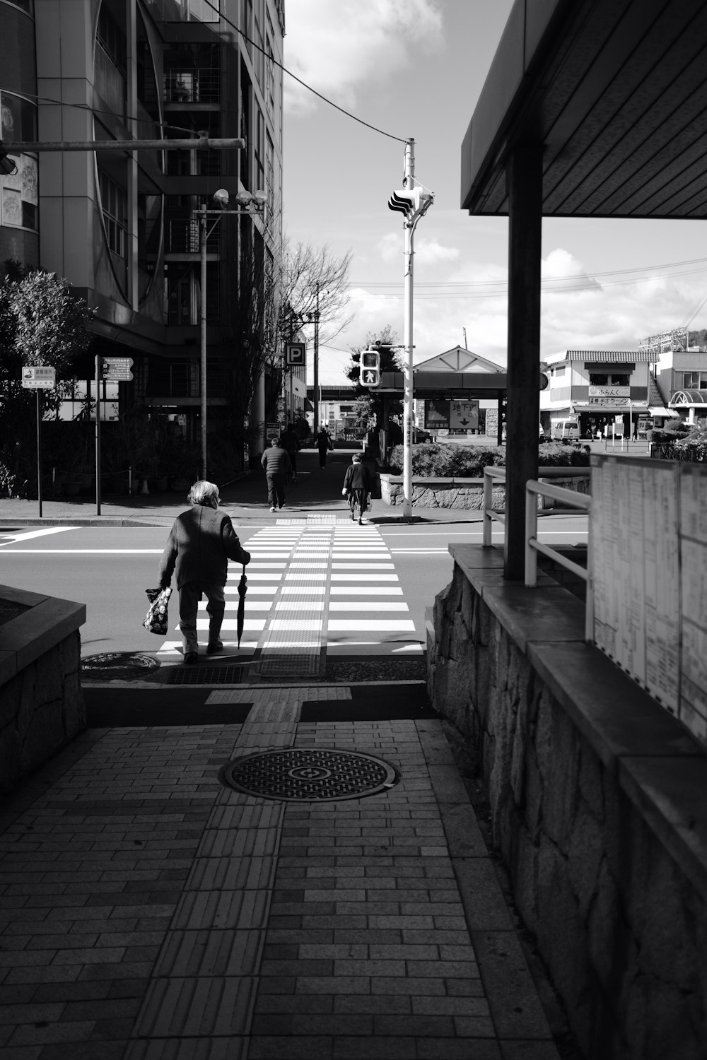 grayscale photo of man and woman walking on sidewalk