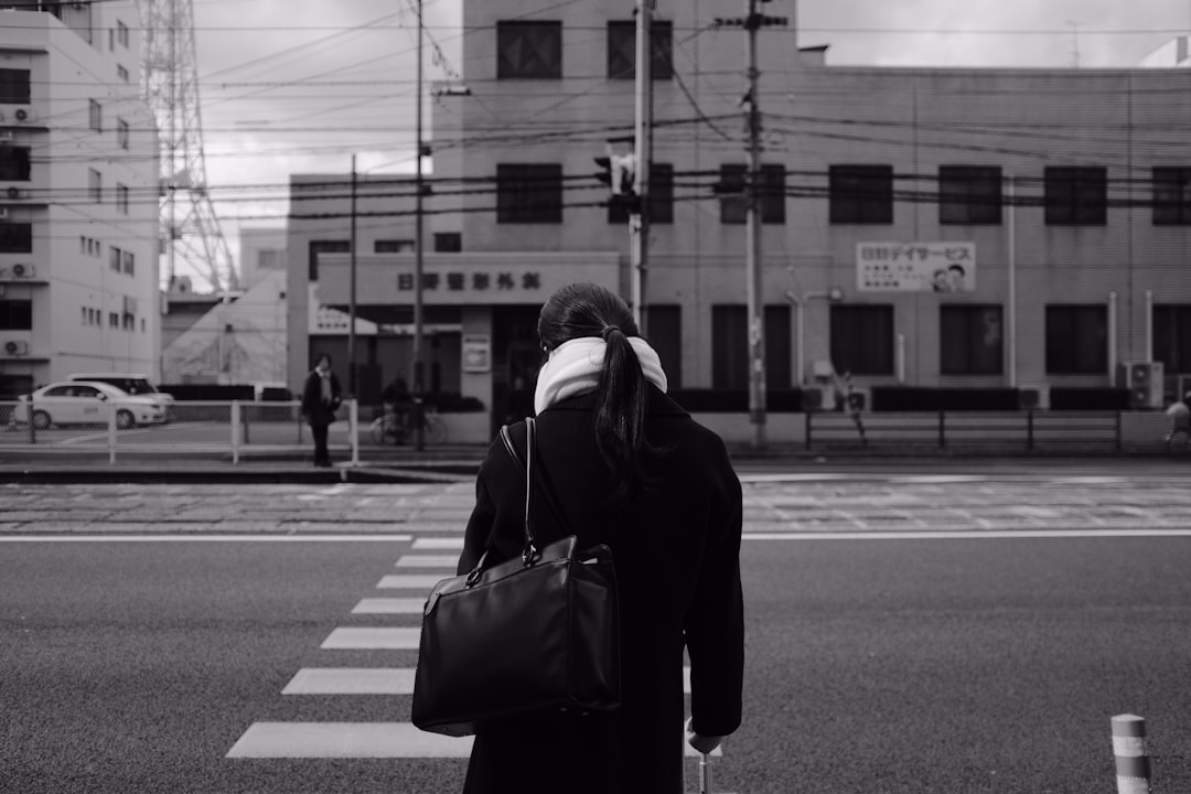 grayscale photo of person in hoodie walking on street