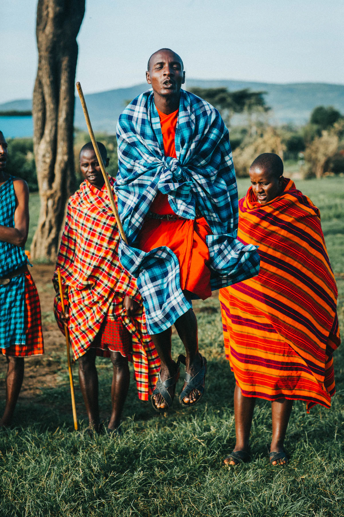 Maasai men in patterned shukas walking together on open highland grassland